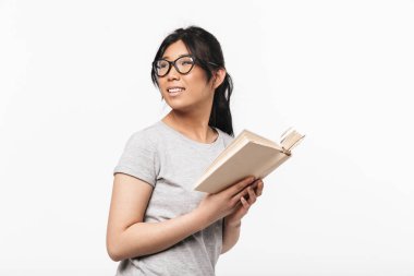 Güzel genç kadın beyaz duvar arka plan tutan kitap okuma üzerinde izole poz.