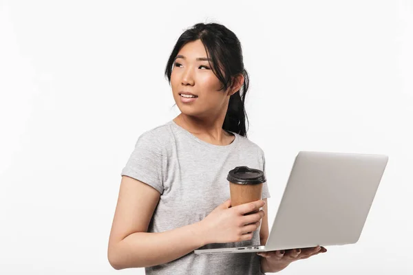Krásná Asijská mladá žena, která v přenosných počítačích představuje izolované pozadí bílé zdi. — Stock fotografie