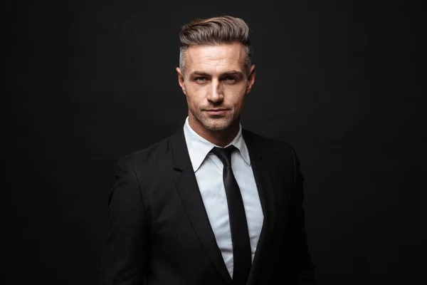 Portrait of serious handsome businessman dressed in formal suit posing and looking at camera — Stock Photo, Image