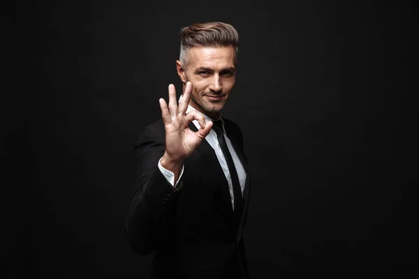 Portret van serieuze mannelijk zakenman gekleed in formeel pak gebaren OK zingen en kijken naar camera — Stockfoto