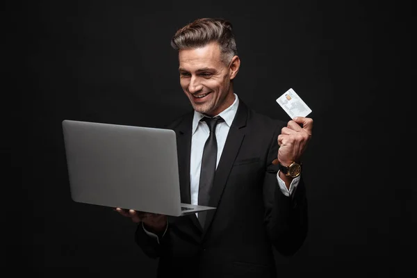 身着正式西装的白种人微笑商人的肖像，手持笔记本电脑和信用卡 — 图库照片