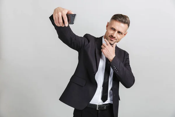 Bild av framgångsrik trygg affärsman i formell kostym röra hans ansikte medan du tar Selfie på mobil — Stockfoto