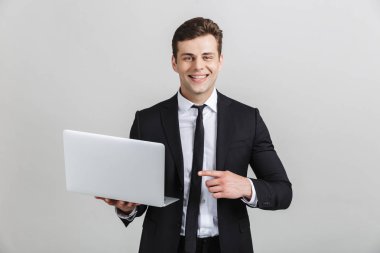 Dizüstü bilgisayarda parmak işaret ederken kamera gülümseyen resmi takım elbiseli çekici esmer işadamı görüntü