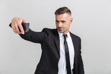 Resmi takım elbiseli başarılı yakışıklı işadamının cep telefonundan selfie fotoğrafı çekerken ki görüntüsü