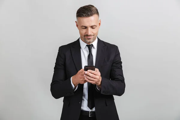 Wizerunek udanego przystojnego biznesmena w formalnym garniturze wpisując na telefon komórkowy — Zdjęcie stockowe