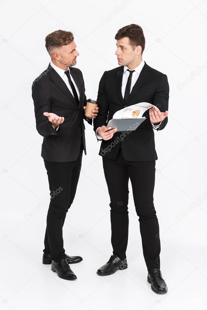 Image of serious two men in office suits holding paper graphs and discussing business