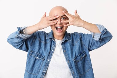 Beautiful happy bald woman posing isolated over white wall background covering face with hands. clipart