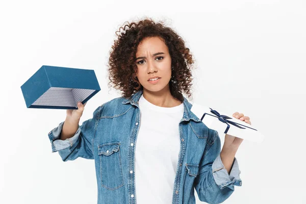 Hermosa mujer africana joven disgustado posando aislado sobre fondo de pared blanca celebración regalo caja . — Foto de Stock