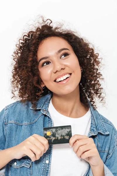 Jovem mulher africana feliz posando isolado sobre fundo parede branca segurando cartão de crédito . — Fotografia de Stock