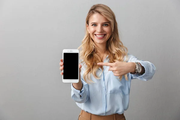 Felice giovane bella donna d'affari bionda posa isolato sfondo grigio muro mostrando visualizzazione del telefono cellulare . — Foto Stock