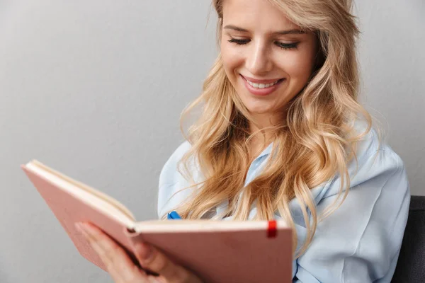 Feliz joven bonita rubia mujer de negocios posando aislado gris pared fondo lectura libro . —  Fotos de Stock