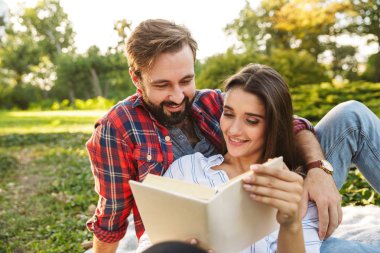 Yeşil parkta dinlenirken memnun çift erkek ve kadın okuma kitap Görüntü