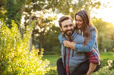 Yeşil parkta güzel bir kadına piggyback binmek veren erkeksi adam Görüntü