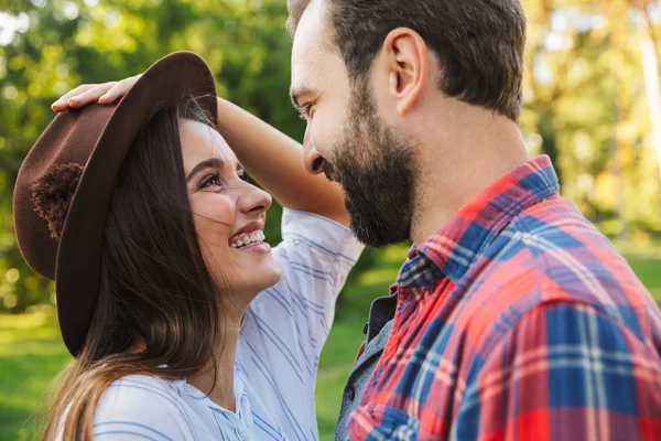 Image of joyful couple man and woman laughing while looking at each other in green park — Stock Photo, Image