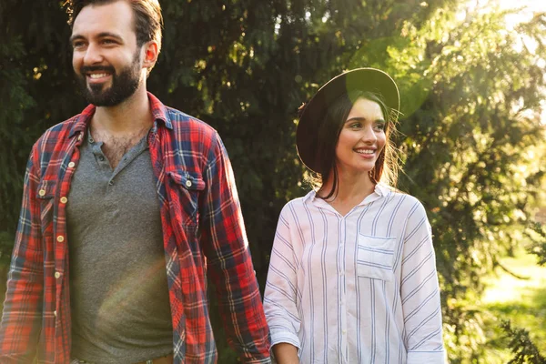 Afbeelding van jong stel man en vrouw glimlachen en wandelen in het groene park — Stockfoto