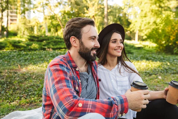 Kép a szép pár férfi és nő iszik elvisz kávét, míg pihenő zöld parkban — Stock Fotó