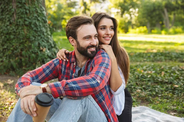 Yeşil parkta dinlenirken romantik çift erkek ve kadın sarılma ve paket kahve içme Görüntü — Stok fotoğraf