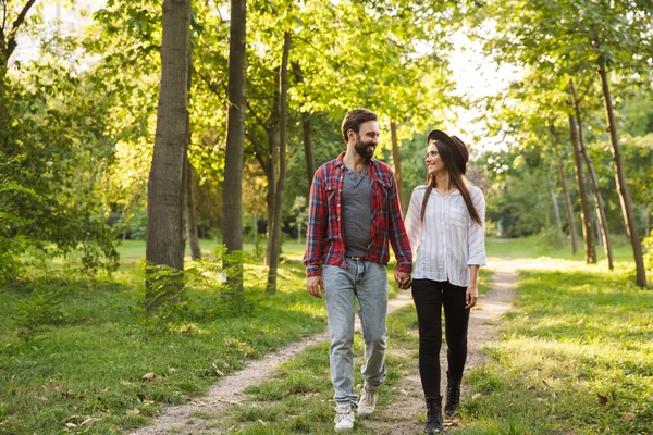 Lächelnd positives junges Liebespaar, das draußen in einem grünen Naturpark-Wald spaziert. — Stockfoto