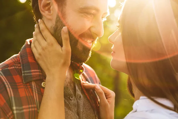 Alegre complacido romántico joven amante pareja caminando al aire libre en un verde parque natural bosque besos . — Foto de Stock