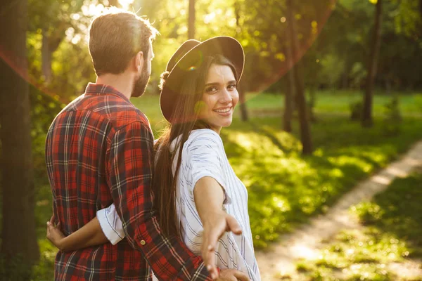 Positive young loving couple walking outdoors in a green nature park forest. — Stock Photo, Image