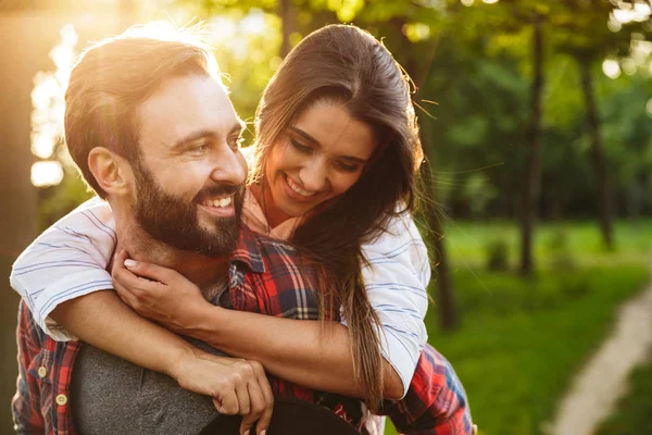 Imagen del hombre masculino dando paseo a cuestas a una mujer bonita en el parque verde —  Fotos de Stock