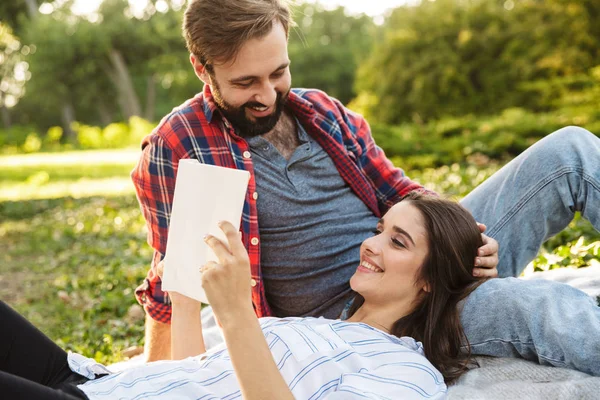 Kép a romantikus pár férfi és nő olvasókönyv pihenő közben a zöld parkban — Stock Fotó