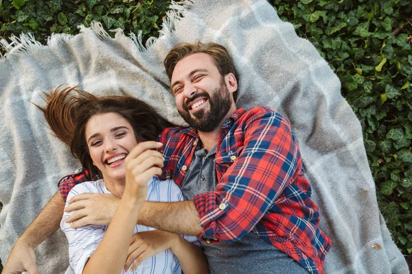 Image de couple joyeux homme et femme étreignant tout en étant couché dans un parc vert — Photo