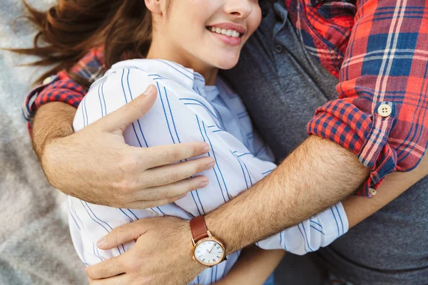 Imagem recortada de jovem casal homem e mulher vestindo relógio de pulso abraçando enquanto deitado — Fotografia de Stock