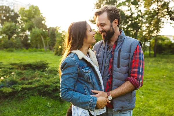 Образ задоволеної пари чоловік і жінка обіймаються і дивляться один на одного під час прогулянки в зеленому парку — стокове фото