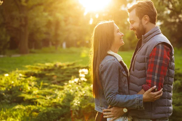 Imagen de pareja feliz hombre y mujer abrazándose y mirándose mientras caminan juntos en el parque verde —  Fotos de Stock