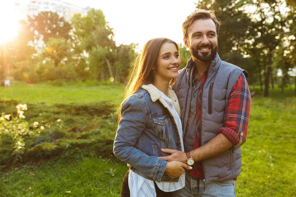 Bild eines schönen Paares, das sich beim gemeinsamen Spaziergang im grünen Park umarmt — Stockfoto