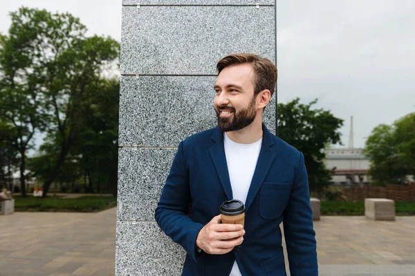 Привлекательный улыбающийся молодой бородатый мужчина в куртке — стоковое фото