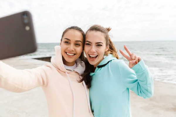 Dos jóvenes y felices mujeres fitness con sudaderas —  Fotos de Stock