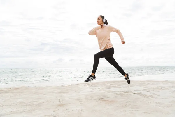 Atractiva joven deportista asiática haciendo ejercicio en la orilla del mar — Foto de Stock