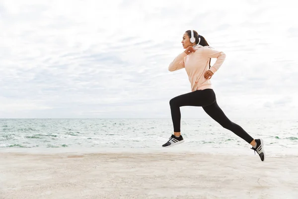 Atractiva joven deportista asiática haciendo ejercicio en la orilla del mar — Foto de Stock