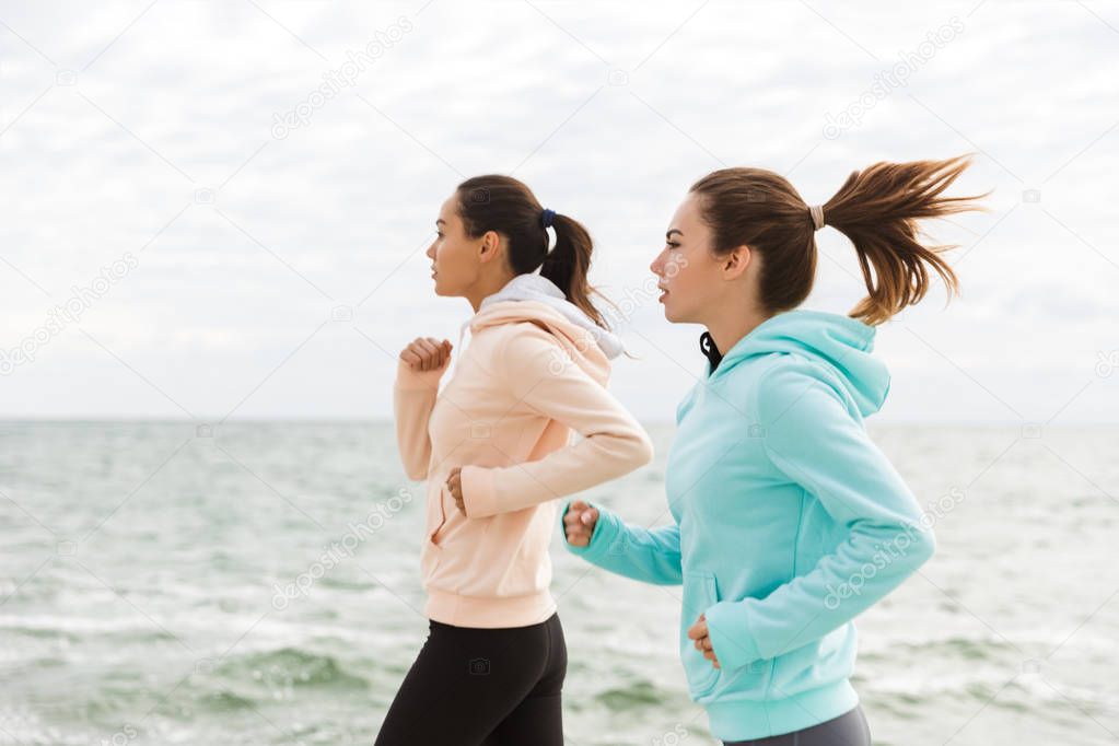 Two beautiful young fitness women jogging outdoors