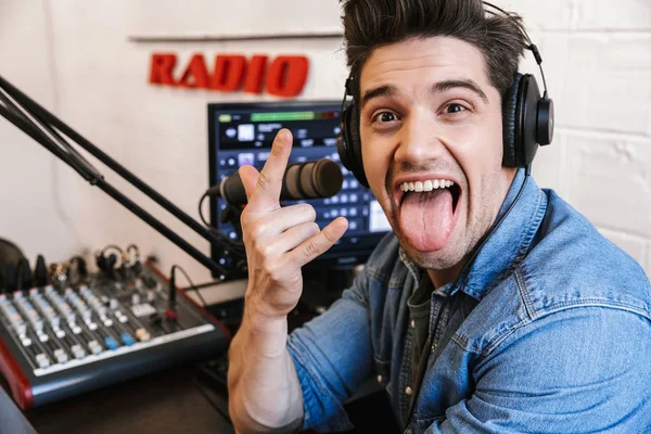 Красивый молодой человек радиоведущий на рабочем месте с микрофоном — стоковое фото