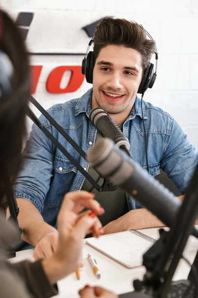 Young man radio host with colleague woman at the workspace with