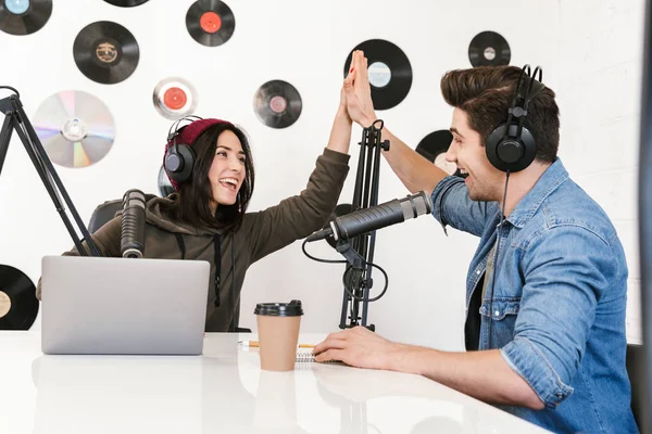 Jeune homme animateur radio avec collègue femme à l'espace de travail avec microphone et équipement sonore parler entre eux . — Photo