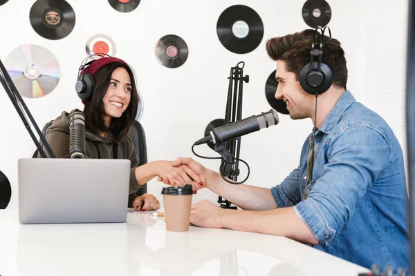 Молодий чоловік радіоведучий з колегою жінкою на робочому місці з мікрофоном і звуковим обладнанням розмовляє один з одним . — стокове фото