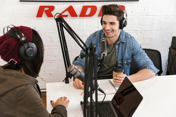 Young man radio host with colleague woman at the workspace with microphone and sound equipment talking with each other. — Stock Photo, Image
