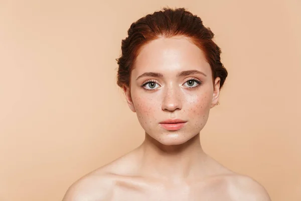 Verbazingwekkende jonge redhead vrouw poseren geïsoleerd over beige muur achtergrond. — Stockfoto