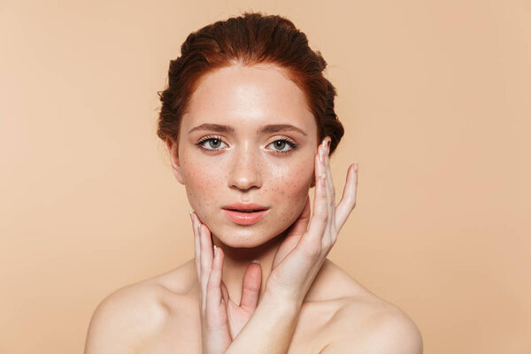 Amazing young redhead woman posing isolated over beige wall background.