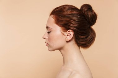 Genç kızıl saçlı kadın bej duvar arka plan üzerinde izole poz.