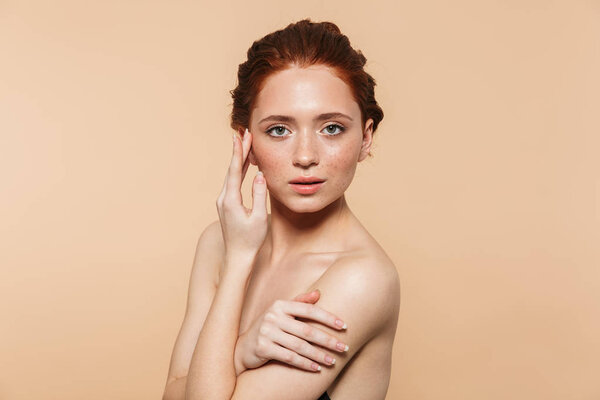 Amazing young redhead woman posing isolated over beige wall background.