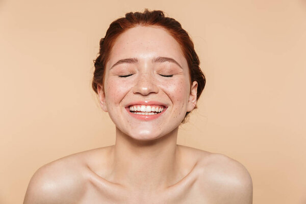 Amazing young redhead woman posing isolated over beige wall background.