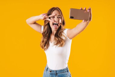Cep telefonuselfie fotoğrafı çekerken barış işareti gösteren temel t-shirt giyen heyecanlı kafkas kadının görüntü yakın çekimi
