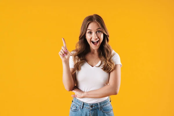 Menina feliz emocional em casual t-shirt branca posando isolado sobre fundo de parede amarelo tem uma ideia apontando . — Fotografia de Stock