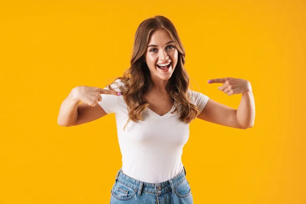 Menina feliz em casual t-shirt branca posando isolado sobre fundo de parede amarelo apontando para si mesma . — Fotografia de Stock