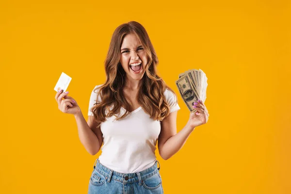 Foto de mujer encantada asombrada regocijándose mientras sostiene fan del dinero del dólar y la tarjeta de crédito — Foto de Stock